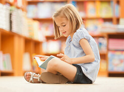 A child reading a book she brought to school in her busy bag.