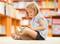 A girl does summer reading at the library.