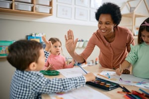 A teacher congratulates a student for getting a correct answer during a spelling game.