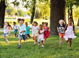 A group of happy children of boys and girls run in the Park on the grass after school.