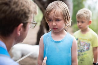 Young boy looks sad and down while his father corrects him for something he did wrong