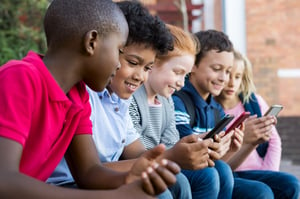 Pupils using mobile phone at the elementary school during recreation time.