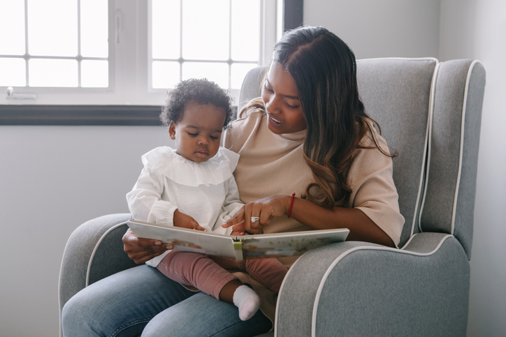 A mom reads to her toddler at home. Early age children education and development. 