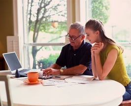 A father teaching his daughter how to open a bank account to save money for the future.