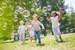 kids playing in the park and chasing bubbles.