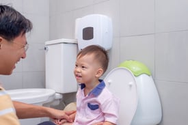 Father teaching son to potty train in a family restroom