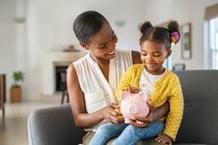 A mom is teaching her young daughter the value of a dollar and how to save money.