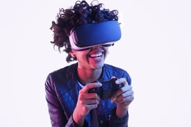 A teen girl using controller and laughing while standing on and playing VR game