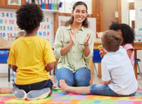 A preschool teacher helping children to learn how to spell.