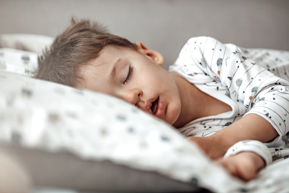 a toddler sleeping in their bed